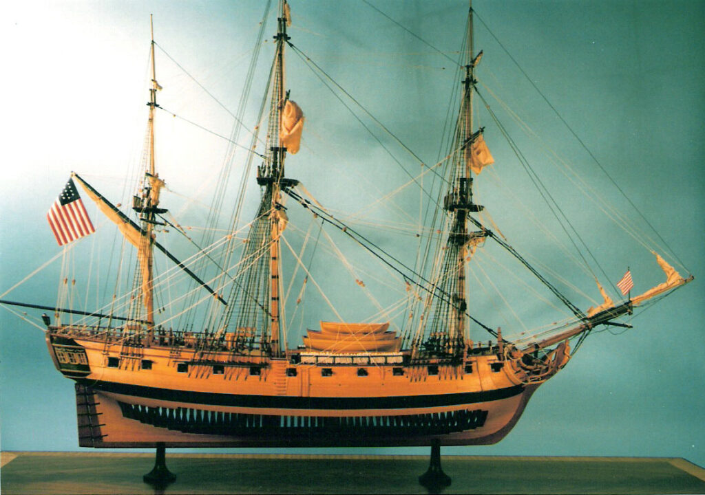 Model of frigate 'Virginia' with model maker in background, view from masthead- view from starboard