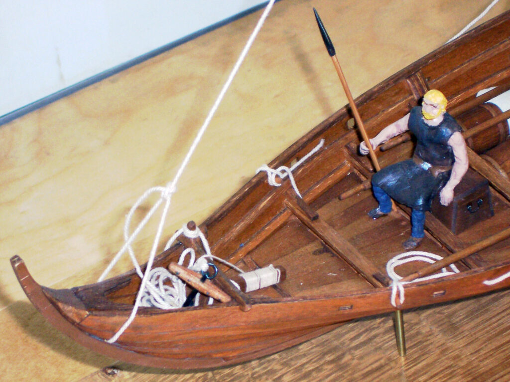 Model of a viking merchant vessel - man wielding spear in bow (passenger?)